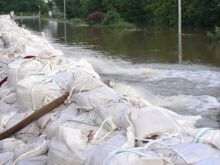Hochwasser wird über gestapelte Sandsäcke mit Feuerwehrschläuchen abgepumt