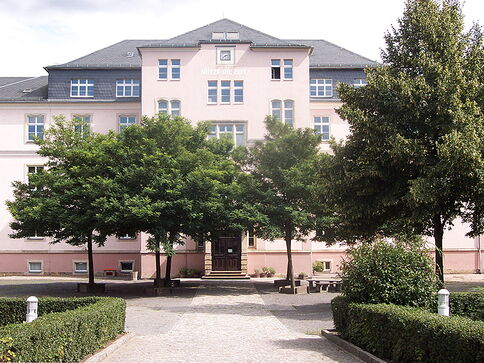 Leonhard-Frank-Oberschule rosafarbenes Schulgebäude mit Bäumen auf dem Schulhof