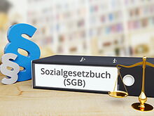Ordner mit Schrift Sozialgesetzbuch, Paragrafenzeichen und Waage
