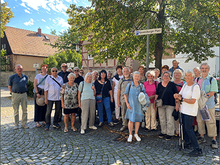 Eine Gruppe steht vor dem Ravensburger Schild am Ravensburger Platz.