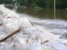 Hochwasser über gestapelte Sandsäcke mit Feuerwehrschläuchen abgepumpt