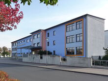 blaues Schulgebäude mit der Aufschrift Gymnasium Coswig an der Fassade