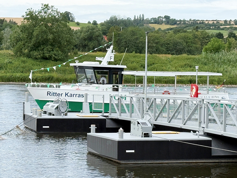 Die weiß-grüne Fähre liegt am Steg in der Elbe